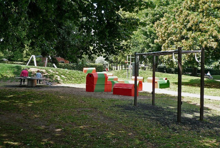 Brightly painted concrete blocks set out as play seating beside a climbing frame