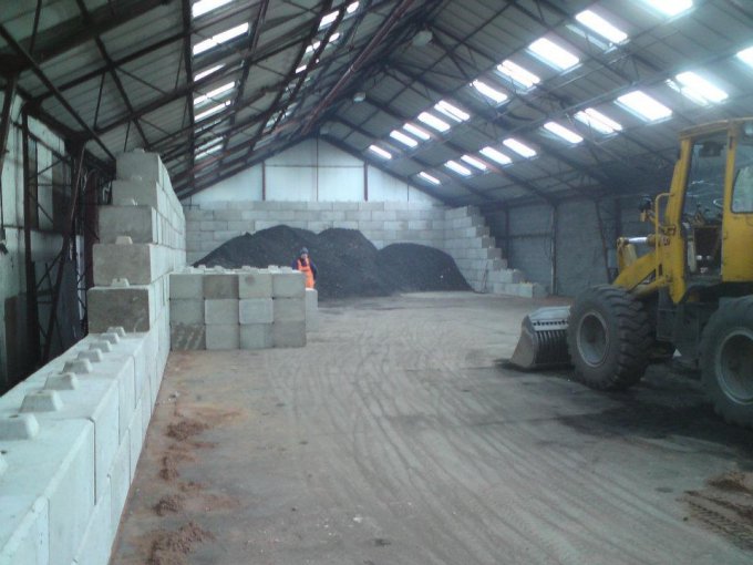 Loading shovel working between Duo block bay walls inside a storage shed