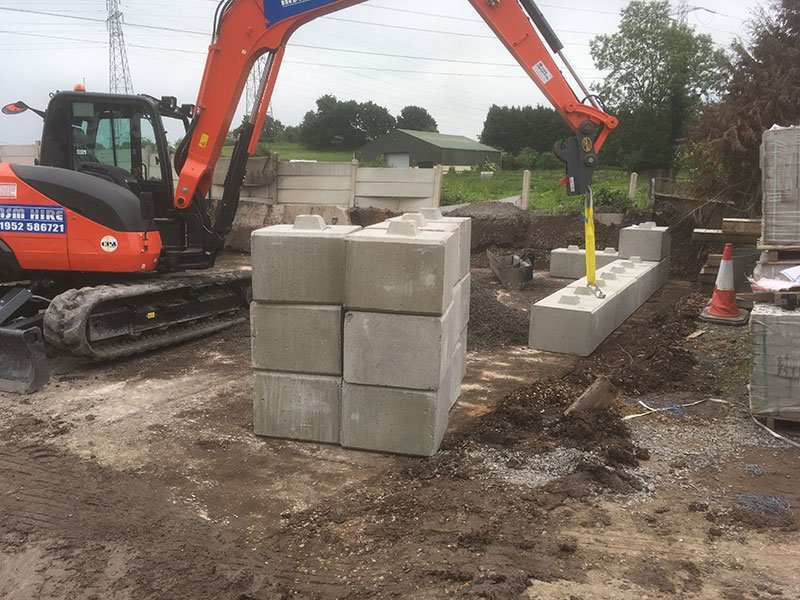 Excavator placing Duo blocks to build material bay walls on site