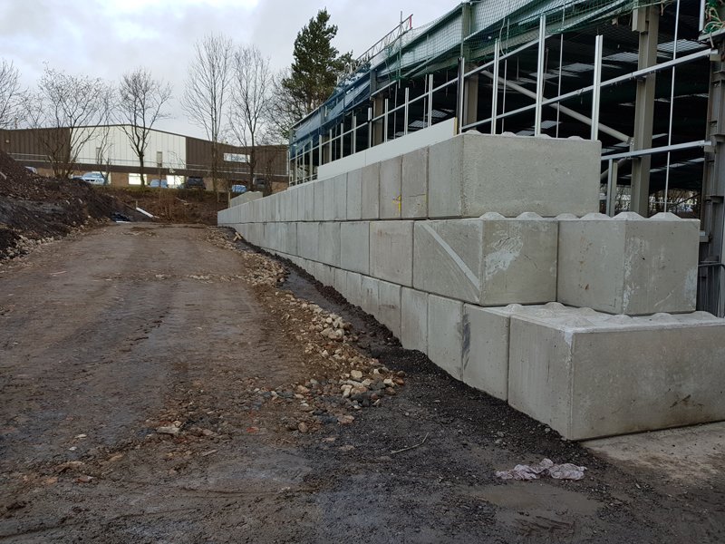 Legato block retaining wall beside a steel-framed unit under construction