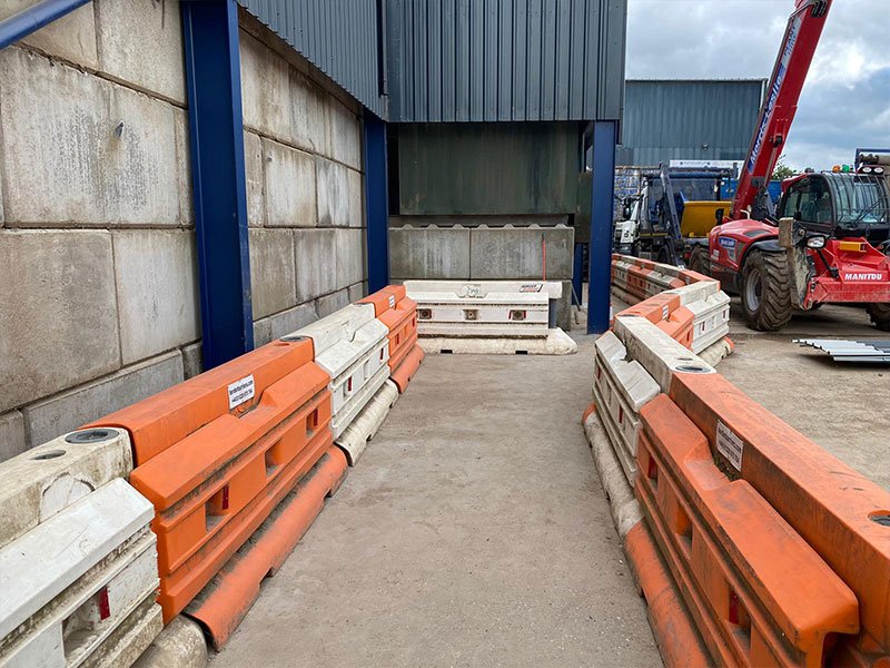 Legato block walls flanking a yard route lined with orange plastic barriers