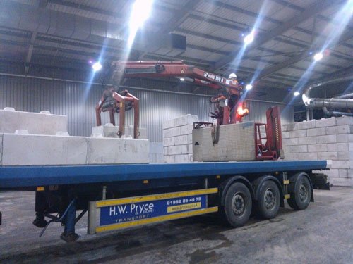 Lorry-mounted crane unloading Duo interlocking blocks from a flatbed trailer indoors