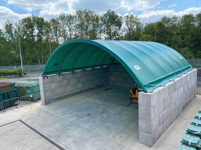 Green arched canopy spanning Legato block walls over a yard