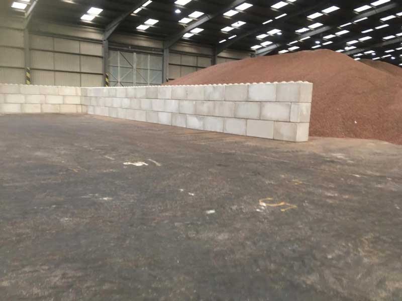 Legato block wall retaining a red sand stockpile inside a warehouse