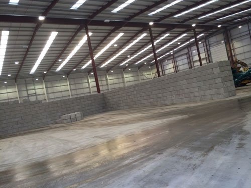 Completed interlocking block wall lining the inside of an empty warehouse