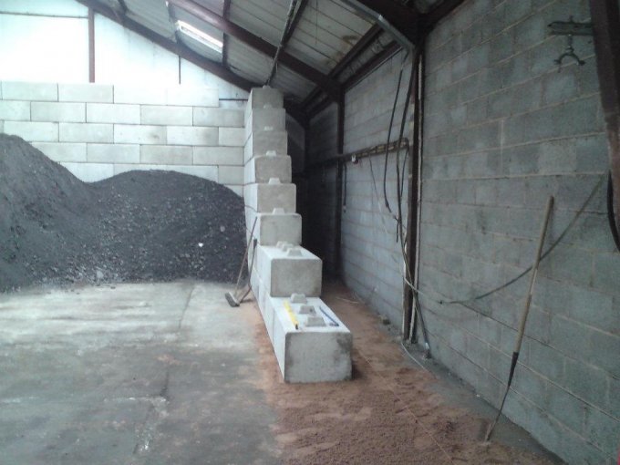 Duo block wall alongside a black aggregate stockpile inside a storage shed