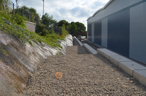 Stepped block walling holding back a steep bank beside an industrial unit