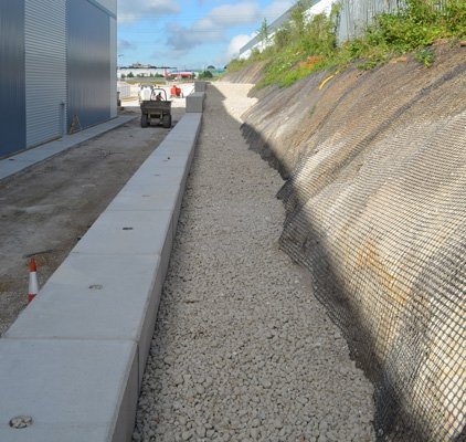 Drainage channel between a block wall top and a geotextile-covered cut slope