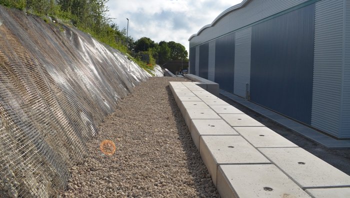 Legato block wall built between a meshed embankment and an industrial unit