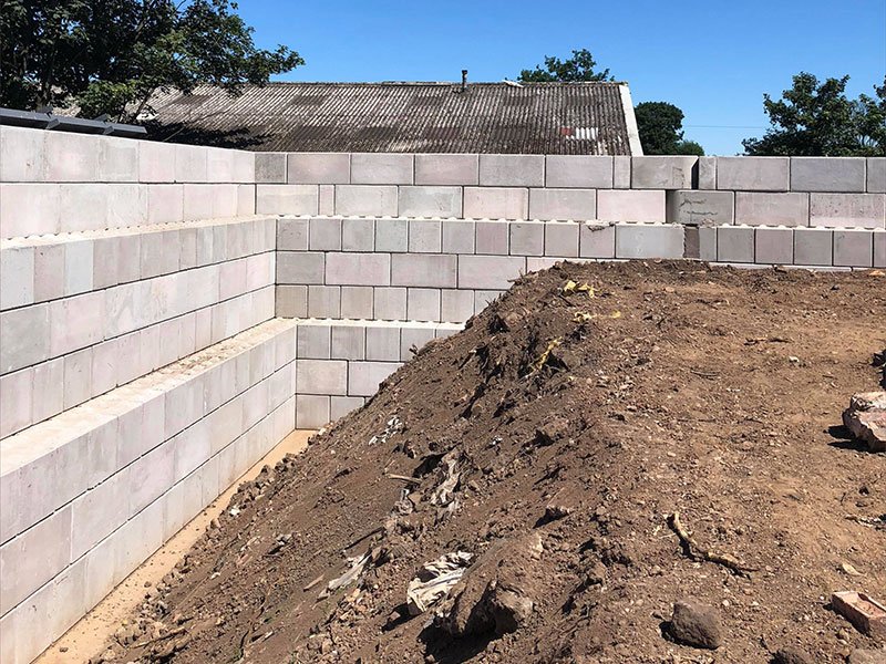 Legato block retaining wall holding back a bank of excavated soil