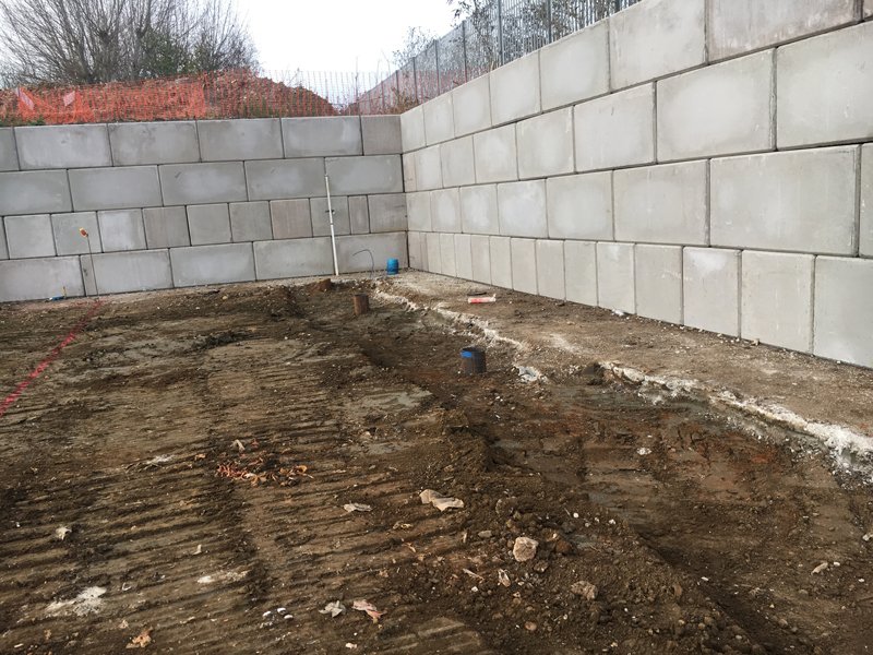 Legato block walls meeting at a corner to retain an excavated compound