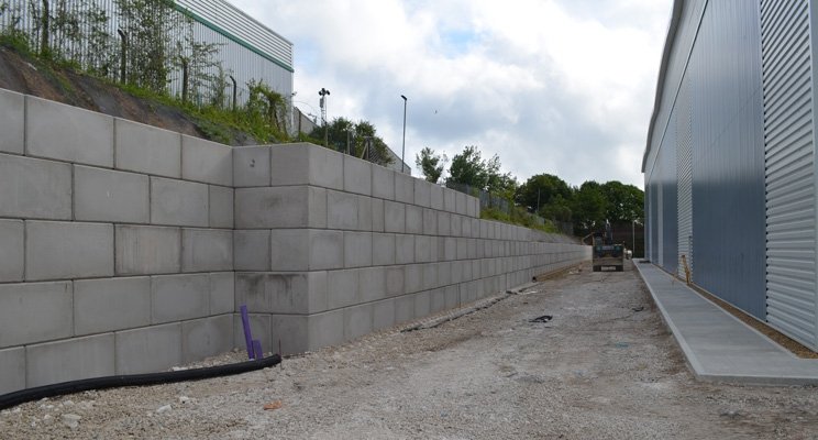 Interlocking block retaining wall holding an earth bank beside an industrial unit
