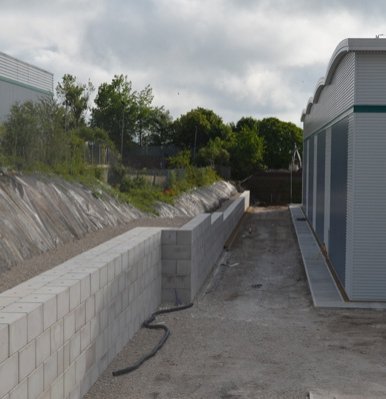 Interlocking block wall retaining a cut slope alongside a new industrial building
