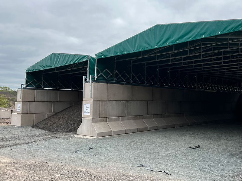 Legato interlocking block wall forming the base of a green covered storage building