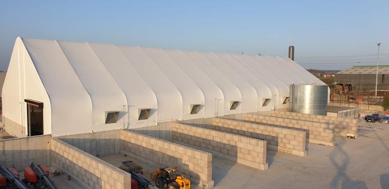 Interlocking block walls forming the base of a white fabric storage building