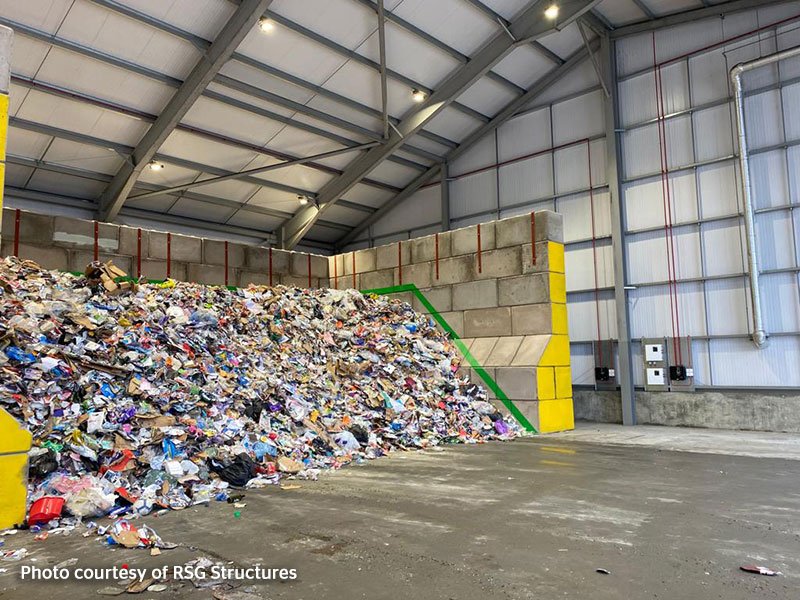 Mixed waste piled against an interlocking block push wall in a recycling shed