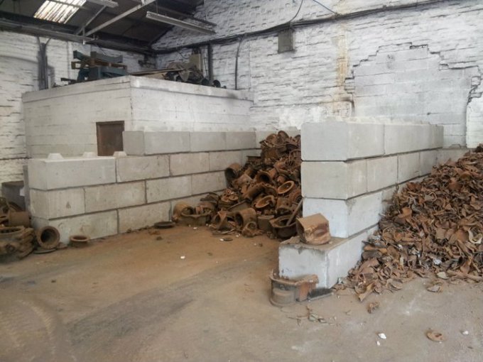 Duo blocks dividing bays of rusted scrap metal against a brick wall