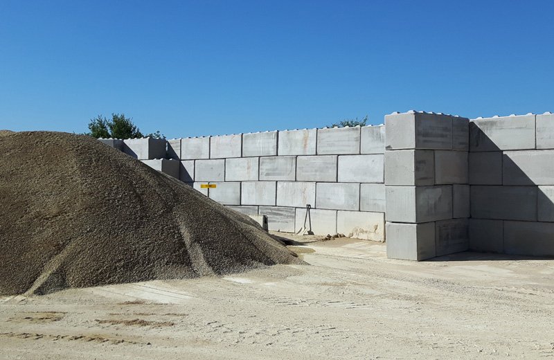 Legato block bays holding a heaped stockpile of aggregate in a quarry yard