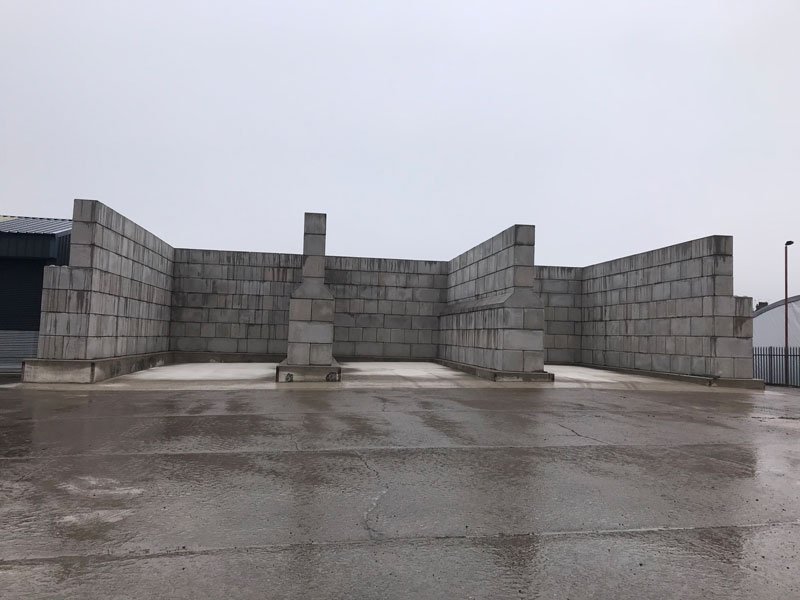 Legato interlocking blocks forming empty storage bay walls on a wet concrete yard
