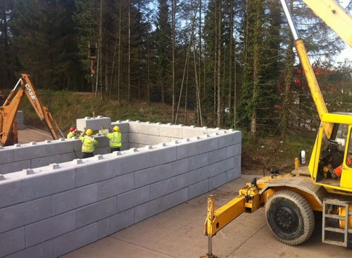 Telehandler and site team building a compost storage bay from interlocking blocks