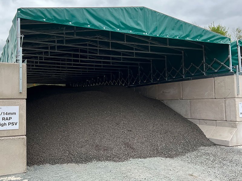 Canopy covered storage bay with interlocking block walls holding aggregate