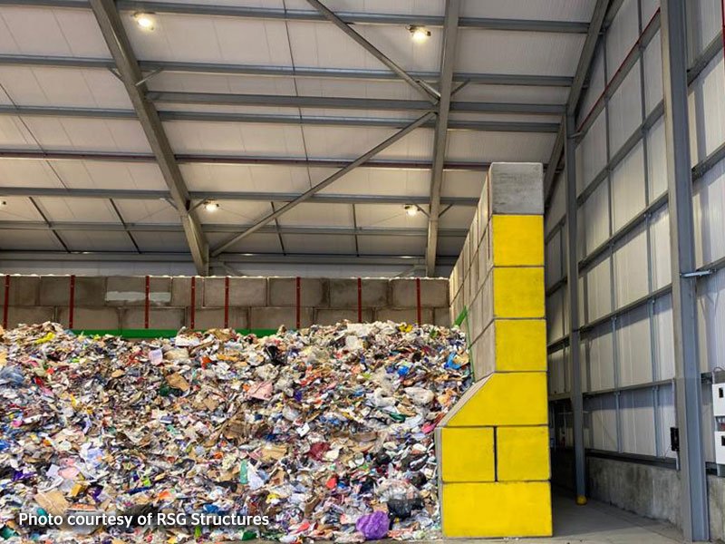 Yellow-painted Legato interlocking block push wall retaining mixed waste inside a transfer shed