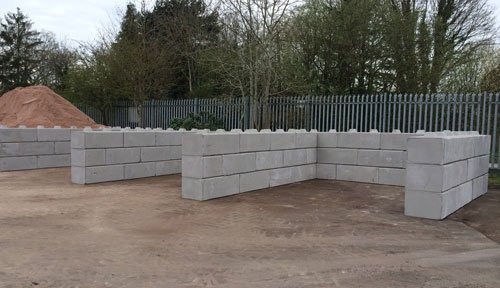Duo blocks forming a low storage bay wall beside an aggregate stockpile