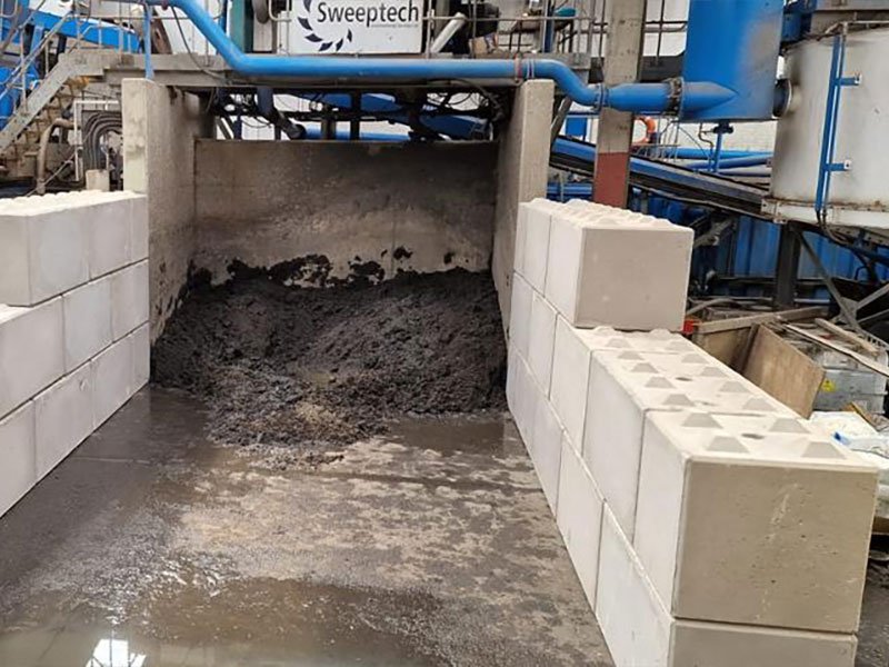 Legato block walls forming a bay holding wet silt at a washing plant