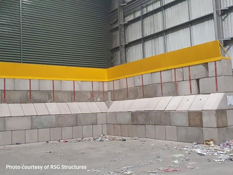 Interlocking block wall with a yellow crash rail forming an internal corner