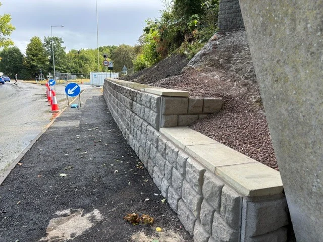 Retainer-Rock walling with coping units retaining a bank beside a roadside footpath