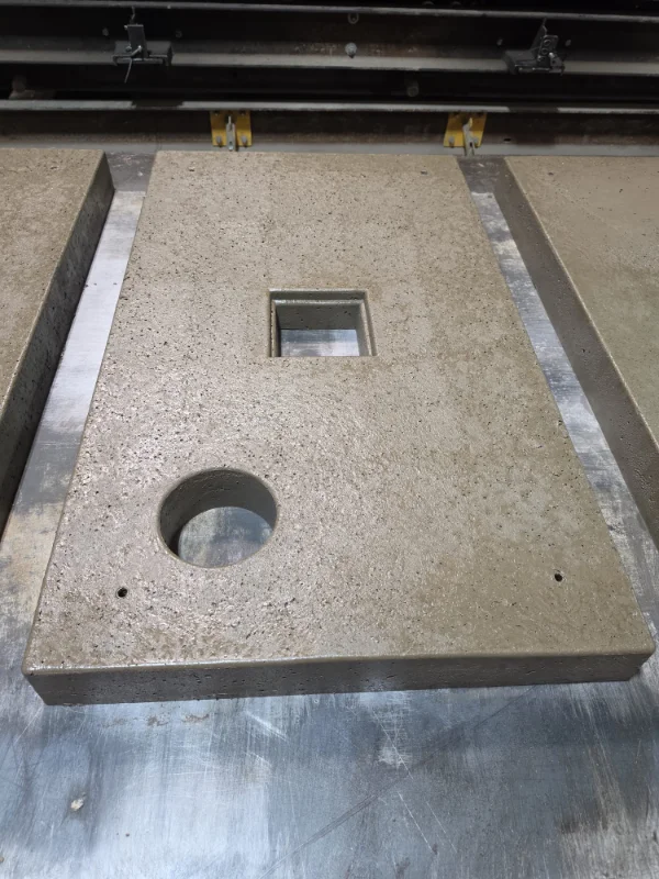 Freshly cast concrete heat pump base in a steel mould with service openings
