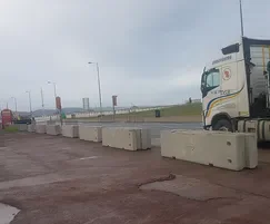 Temporary concrete barriers spaced across a promenade with a delivery lorry behind