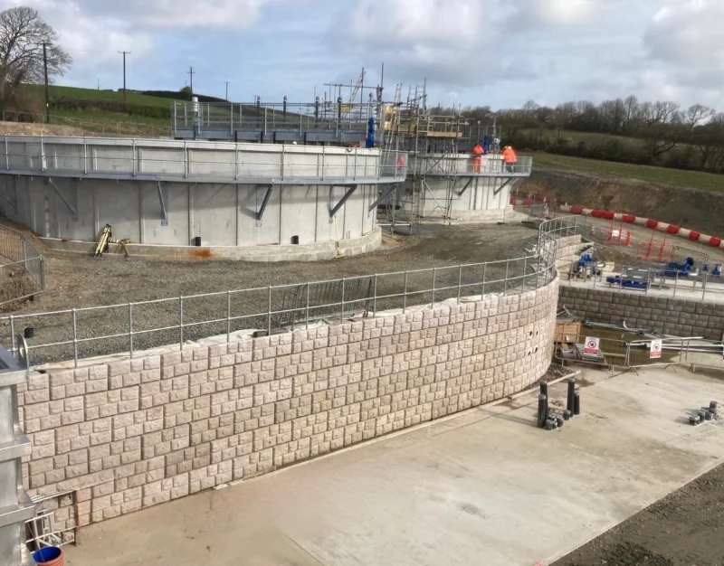 Retainer-Rock walling retaining ground beside circular concrete tanks under construction